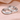 Dos anillos de pareja de acero inoxidable plateado grabados con love you y forever sobre satén rosa