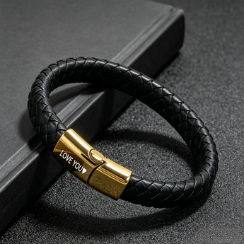 Black braided bracelet with a gold-tone clasp engraved with LOVE YOU on a dark surface