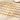 Gold paperclip chain bracelets with letter charms A to F and round coin charms laid flat