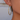 Side view of a thin gold-tone large hoop earring worn through the earlobe