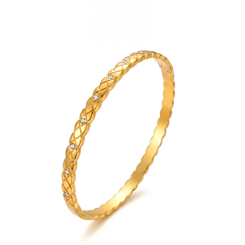 Pulsera rígida dorada de rombos de pie sobre fondo claro