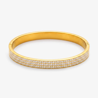 Brazalete rígido de acero inoxidable en tono dorado con tres filas de piedras transparentes sobre fondo blanco