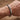 Primer plano de la pulsera de cadena de acero inoxidable color plata en la muñeca, fondo de madera