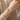 Pulsera de barra curva en tono plateado con dije de moño, usada en la muñeca