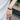 Black braided bracelet charging cable worn on a wrist against a railing background