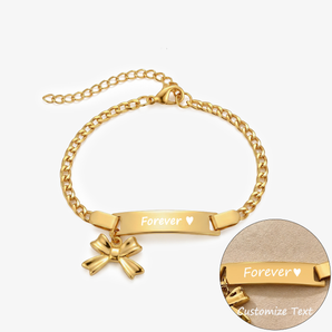 Pulsera dorada de barra curva con dije de moño, grabada con Forever y un corazón, con un primer plano del grabado